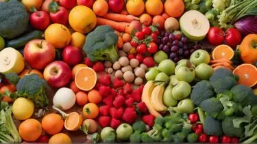Et farverigt udvalg af friske frugter og grøntsager, herunder æbler, appelsiner, bananer, jordbær, vindruer, gulerødder, broccoli og meloner, arrangeret tæt sammen på en flad overflade.