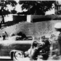 Limousinen med blandt andre USA's præsident John F. Kennedy i sekunderne efter, at et dødbringende skud har ramt ham i hovedet. Omkring 50 vidner forklarede bagefter, at de havde hørt skud eller set aktivitet på græshøjen bagest i billedet. (Foto: Mary Moorman)