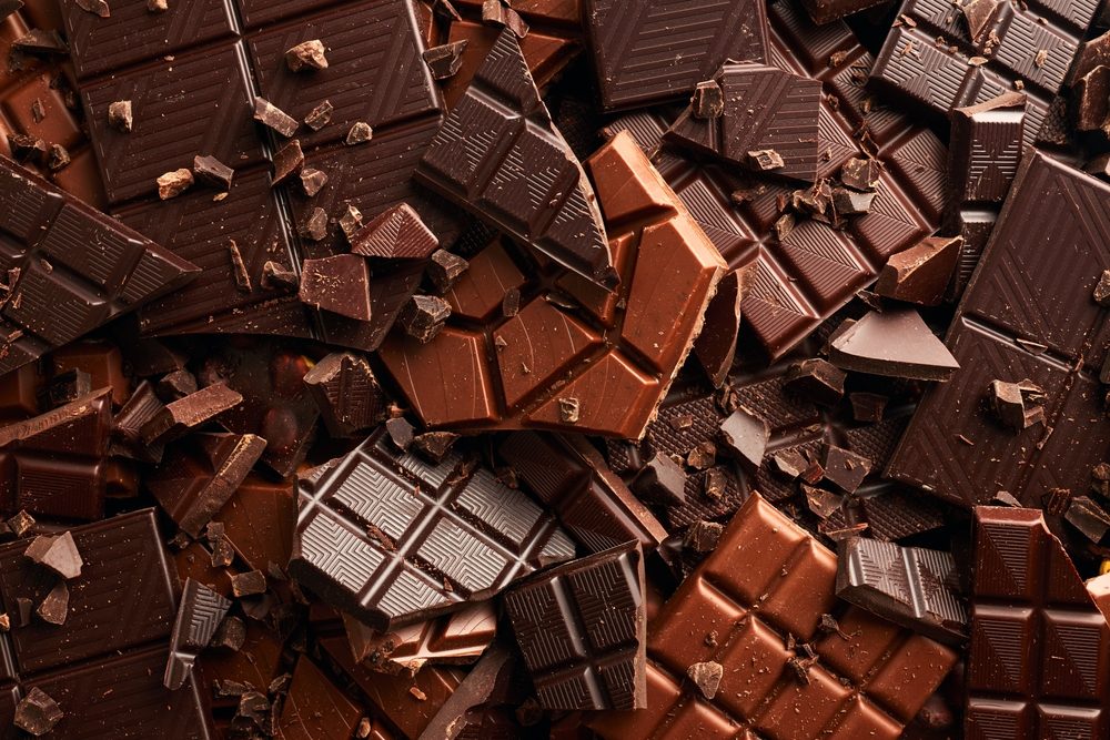 En masse knækket mørk og lys chokolade i en stor bunke.