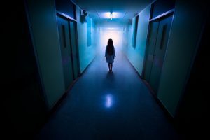 Mareridtsagtig scene, lille pige står alene i en lang, uhyggelig hospitalsgang