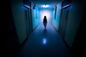 Mareridtsagtig scene, lille pige står alene i en lang, uhyggelig hospitalsgang