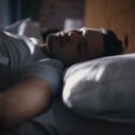 En mand ligger i sin seng og sover