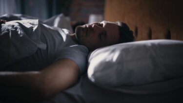 En mand ligger i sin seng og sover