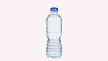 En vandflaske i klar plast med blå hætte, fyldt med vand, står oprejst mod en almindelig lyserød baggrund.