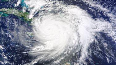 Satellitbillede af en stor orkan over Det Caribiske Hav, som viser et veldefineret øje og hvirvlende hvide skyer, der breder sig ud over havet og de nærliggende landområder.