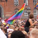 En menneskemængde er samlet foran rådhuset i København. Regnbue-prideflag vejrer i vinden