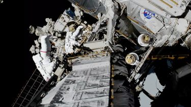 Astronauterne Christina Koch (i forgrunden, dragt med rød stribe) og Jessica Meir (dragt uden striber) udskiftede en batterioplader på den første rumvandring kun med kvinder nogensinde. Foto: NASA TV.