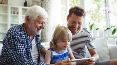 Tre generationer af mænd i en familie sidder med en iPad