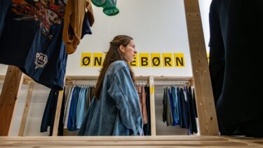 En kvinde går forbi et skilt i et tøjbutik, hvor der står 'ønskebørn'