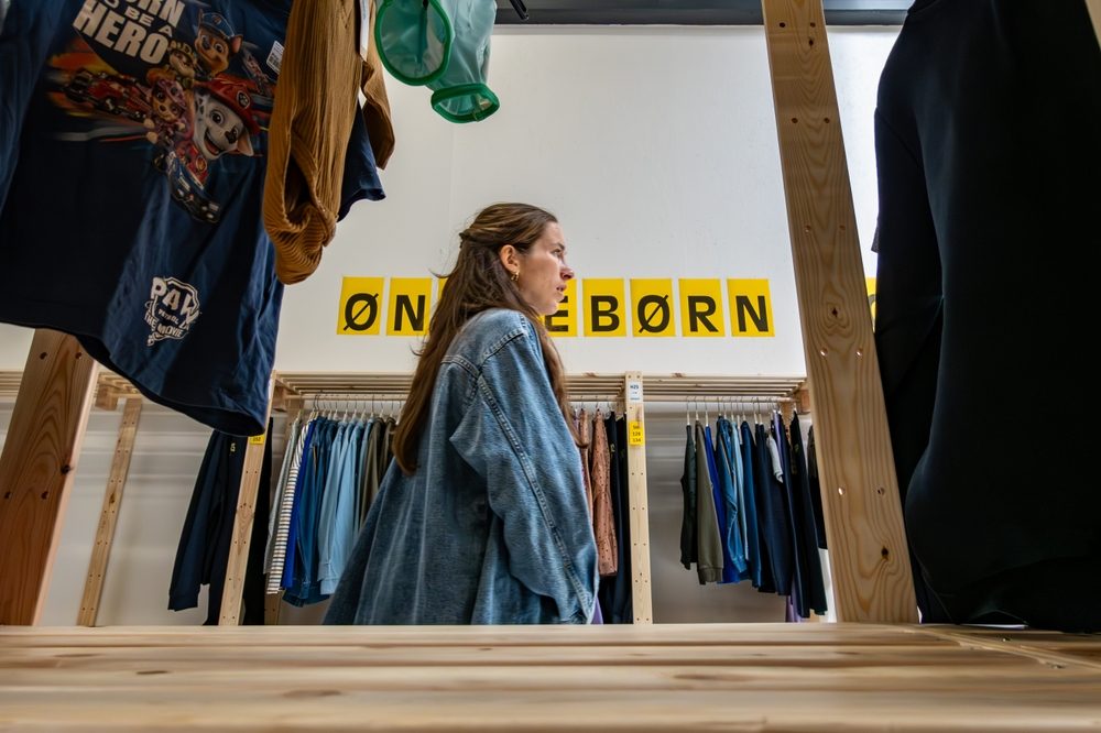 En kvinde går forbi et skilt i et tøjbutik, hvor der står 'ønskebørn'