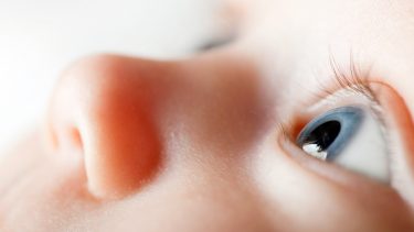 Nærbillede af en babys ansigt. Spædbarnet kigger intenst op mod loftet.