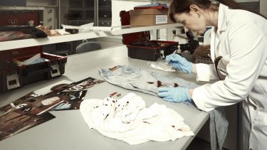 Forsker undersøger blodigt tøj i et laboratorie