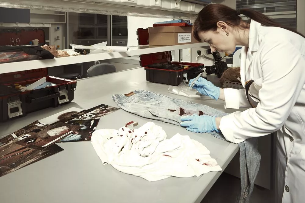 Forsker undersøger blodigt tøj i et laboratorie