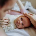 Baby på puslebord kigger op på forælderen