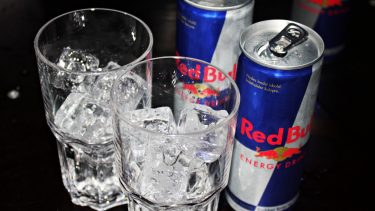 To dåser med Red Bull står ved siden af to glas med isterninger
