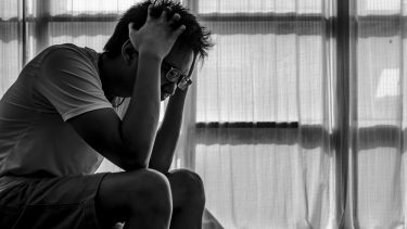 Person med stress sidder på kanten af sin seng