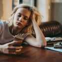 Ung kvinde kigger på sin telefon i stedet for at studere
