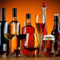 Forskellige typer alkohol, vist både i glas og på flasker, mod en orange baggrund.