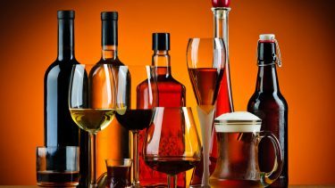 Forskellige typer alkohol, vist både i glas og på flasker, mod en orange baggrund.