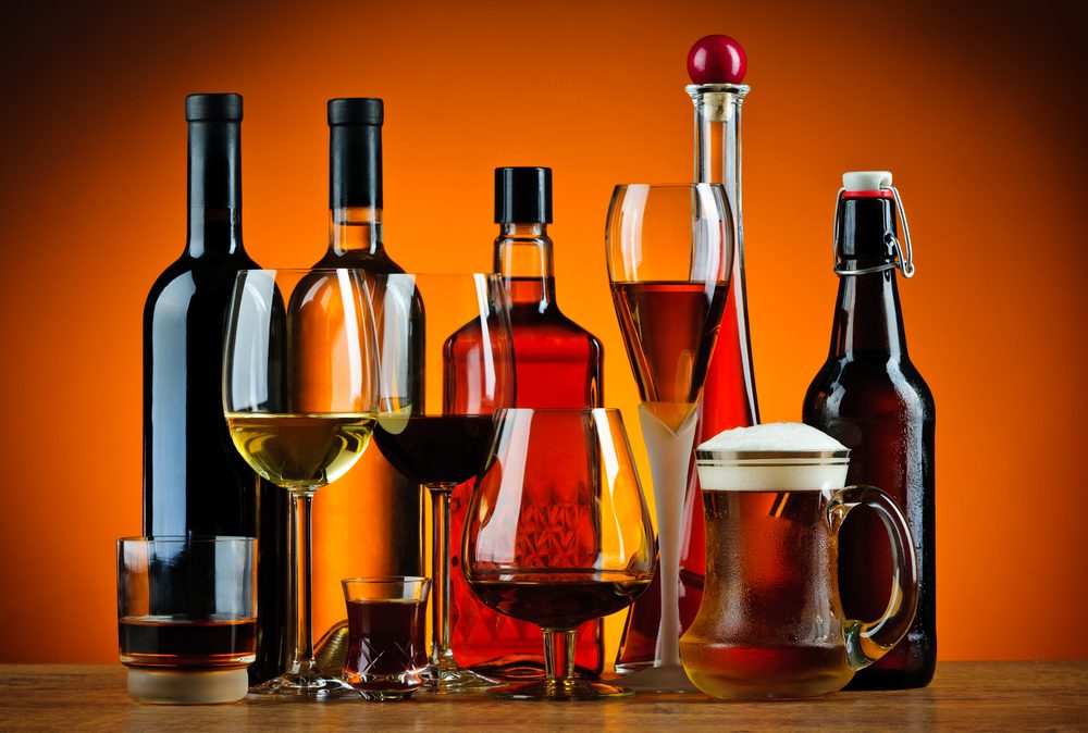 Forskellige typer alkohol, vist både i glas og på flasker, mod en orange baggrund.