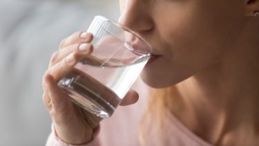 Nærbillede af kvinde, der drikker vand af et glas