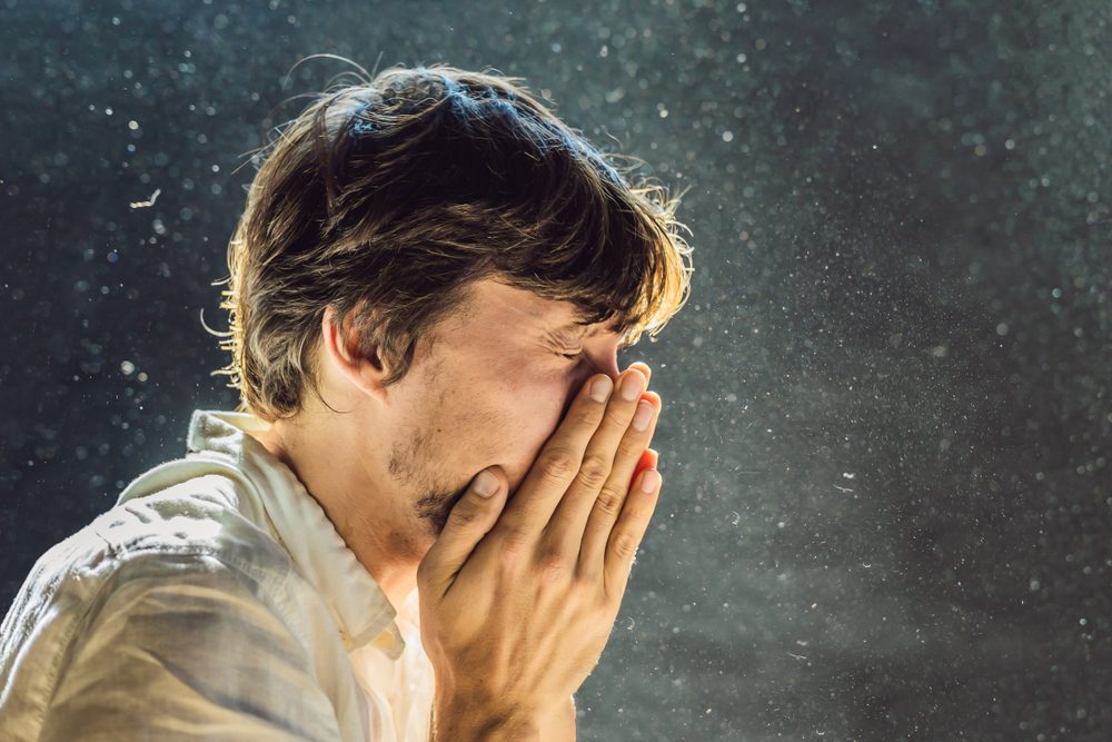 Man, der nyser, fotograferet i modlys