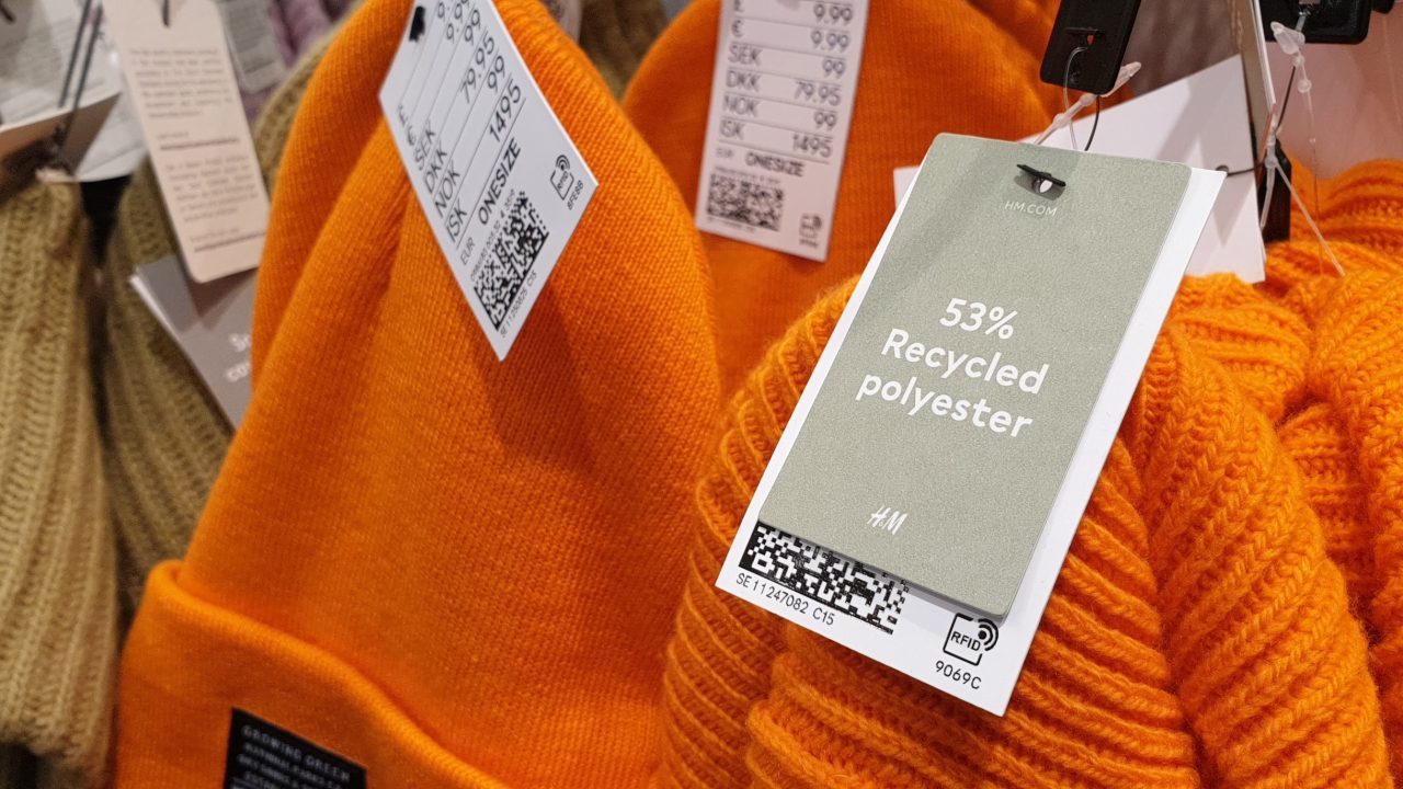 Orange tøj af genbrugspolyester hænger på stativ