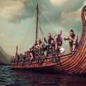 Foto af vikingeskib med vikinger ombord mod en truende aftensky