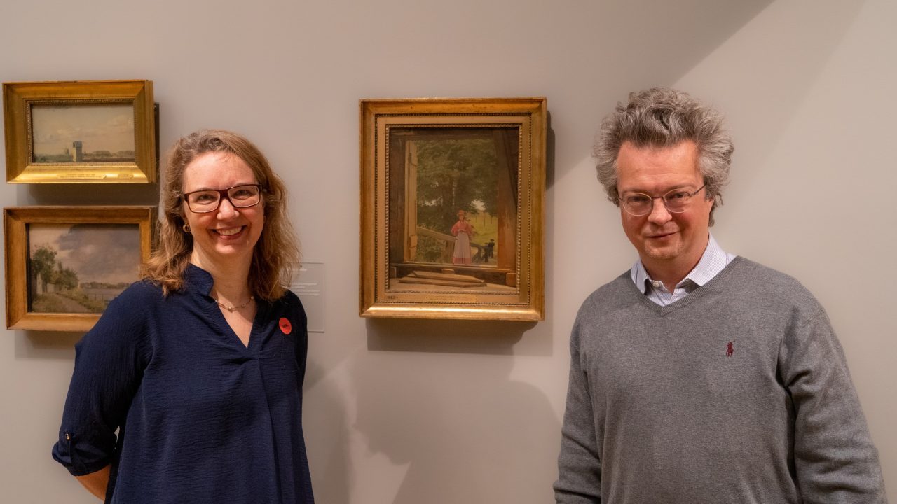 To af forskerne bag -Enrico Cappellini og Cecil Krarup Andersen - foran et af de undersøgte malerier: C.S. Købkes “Udsigt fra loftet på Kornmagasinet ved bageriet i Kastellet" fra 1831.