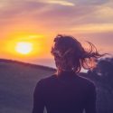 Kvinde med ryggen til ser på smuk sommer-solnedgang