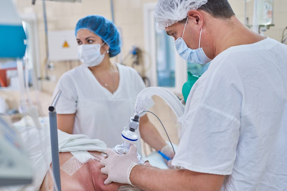 Anæstesilæge bedøver patient, i baggrunden står en sygeplejerske med blåt hårnet