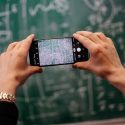 Mand fotograferer tavle med sin mobiltelefon. Der er kompliceret algebra skrevet op på tavlen.