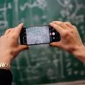 Mand fotograferer tavle med sin mobiltelefon. Der er kompliceret algebra skrevet op på tavlen.