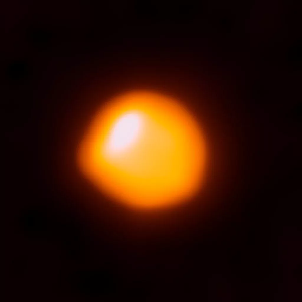 Stjernen Betelgeuse: En klart glødende gul stjerne med en hvid plet og stærk orange aura på en kulsort himmel. Den ligner næsten en radioaktiv æggeblomme.