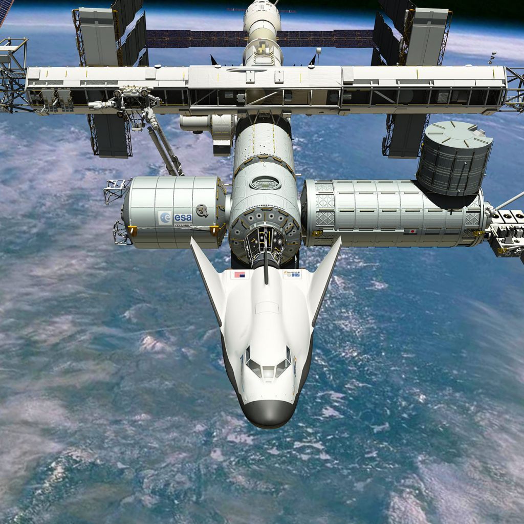 Den lille rumfærge Dream Chaser, der er hvid, trekantet og lidt ligner en båd, ligger til ved ISS.