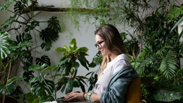 Kvinde omgivet af grønne, frodige planter