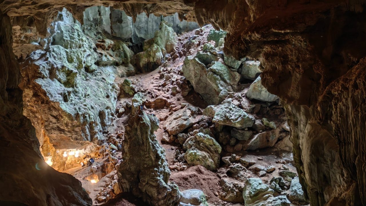 Dyb grotte indeholder skrænt og udgravning med lamper i bunden.