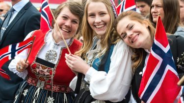 Norske kvinder står med flag i nationaldragter