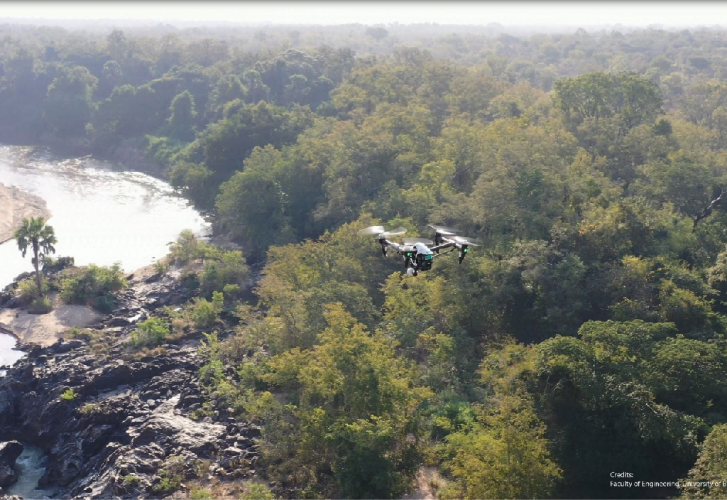 Drone der flyver over træer og floder i Afrika
