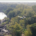 Drone der flyver over træer og floder i Afrika