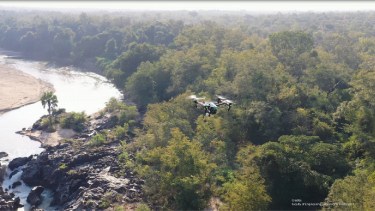 Drone der flyver over træer og floder i Afrika