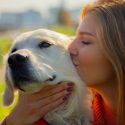 Kvinde kysser golden retriever på kinden