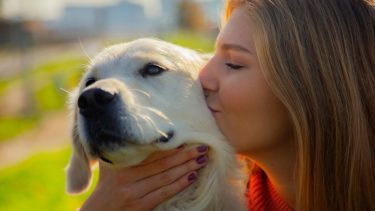 Kvinde kysser golden retriever på kinden