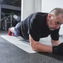 Mand med gråt hår laver planken i fitness centeret