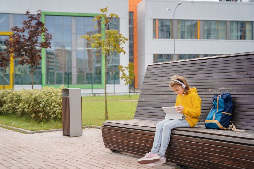 Pige sidder alene i skolegård