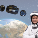 Andreas Mogensen i astronautdragt står foran Jorden og VR-briller svæver i luften over ham