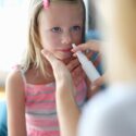 Lille pige bliver vaccineret mod influenza med næsespray