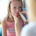 Lille pige bliver vaccineret mod influenza med næsespray
