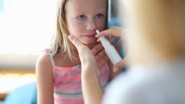 Lille pige bliver vaccineret mod influenza med næsespray