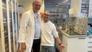 Morten Meldahl står i laboratoriet iført hvid kittel sammen med ph.d.-studerende, Yuan Zhang